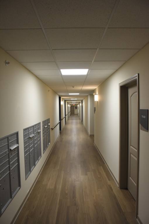 A long hallway with doors on the right and mailboxes on the left.