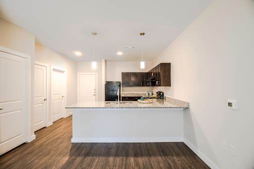 A kitchen with a white island and dark wood floors.
