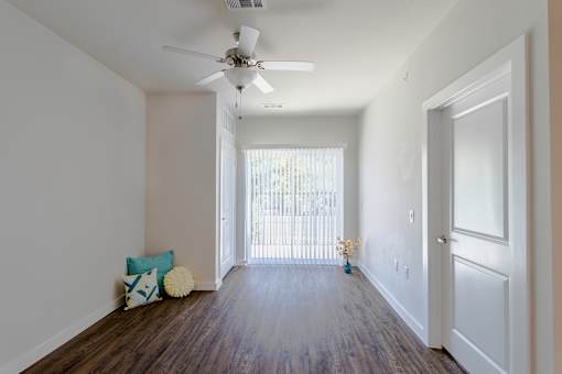 A room with a ceiling fan and a door leading to a balcony.