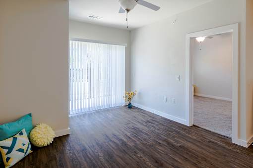 A room with a ceiling fan and a window with blinds.