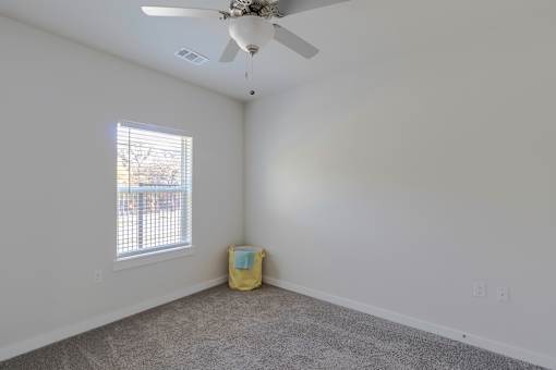 A room with a ceiling fan and a window with blinds.