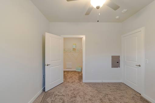 A room with a ceiling fan and carpeted floor.