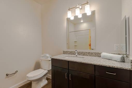 A bathroom with a toilet, sink, and mirror.