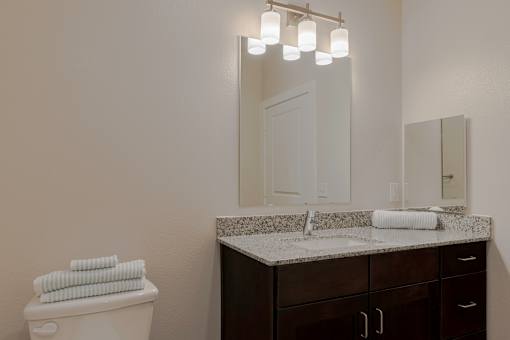 A bathroom with a toilet, sink, and mirror.