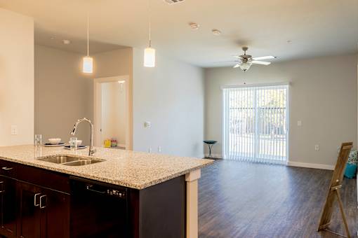 A kitchen with a sink, a counter, and a ceiling fan.