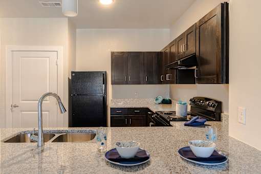 A kitchen with black appliances and granite countertops.