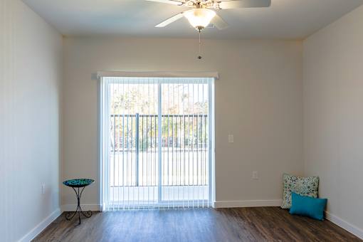 A room with a sliding glass door and a ceiling fan.