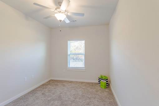 A room with a ceiling fan and a window.