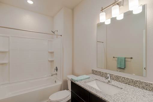 A white bathroom with a toilet, sink, and a mirror.