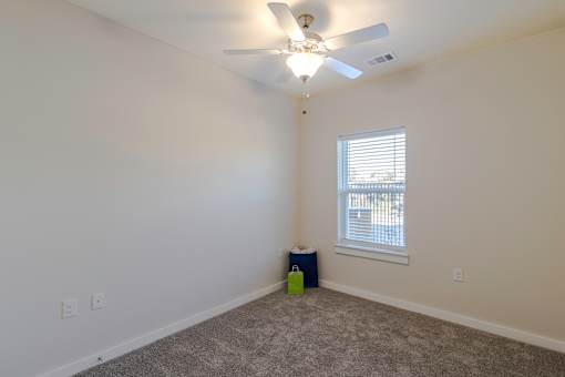 A room with a ceiling fan and a window with blinds.
