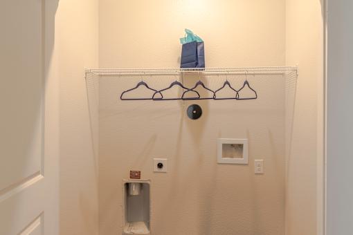 A white wall with a coat hanger and a towel rack.