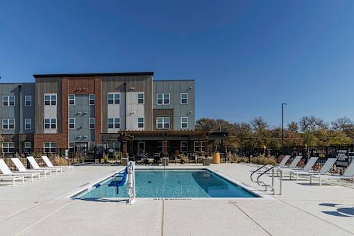A pool area with sun loungers and a building in the background.