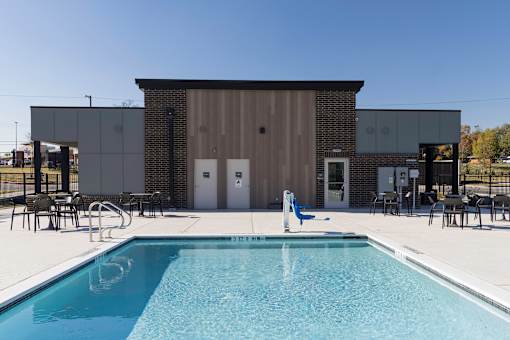 A pool in front of a building with a black and white striped wall.