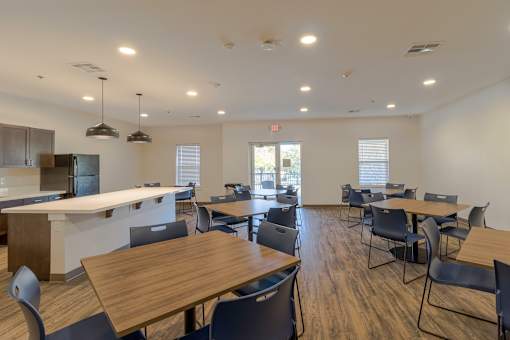 A large room with tables and chairs and a kitchen area.