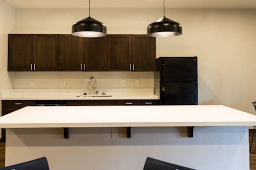 A modern kitchen with dark brown cabinets and white countertops.