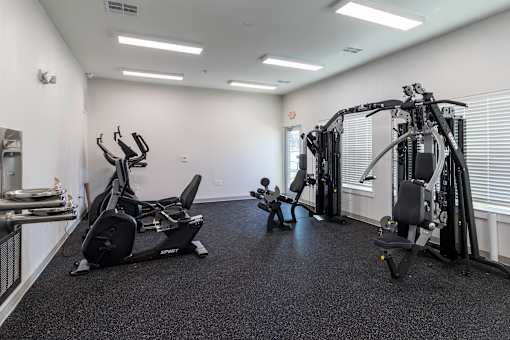 A gym with a variety of equipment including a treadmill, stationary bike, and weight machines.