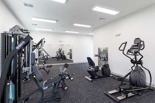 A gym with a variety of equipment including a leg press machine, a rowing machine, and a weight bench.