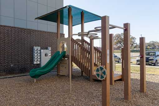 A playground with a green slide and a wooden structure.