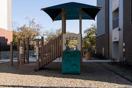 A playground with a wooden structure and a blue trash can.
