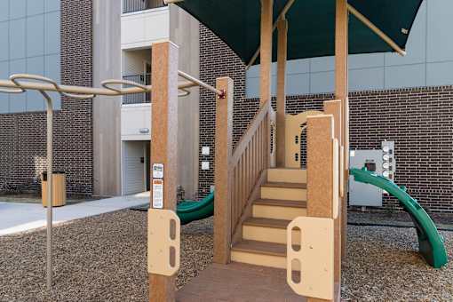 A playground with a slide and a wooden staircase.