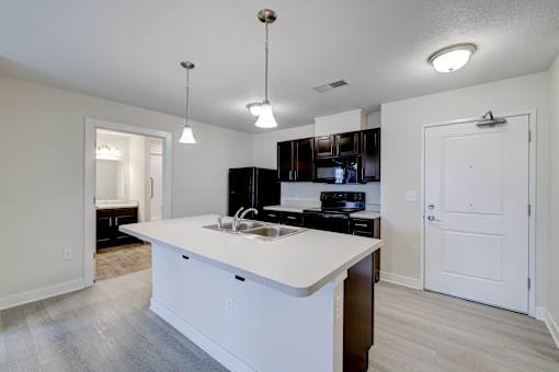A kitchen with a white countertop and a black refrigerator.
