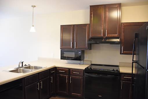 A kitchen with black appliances and brown cabinets.