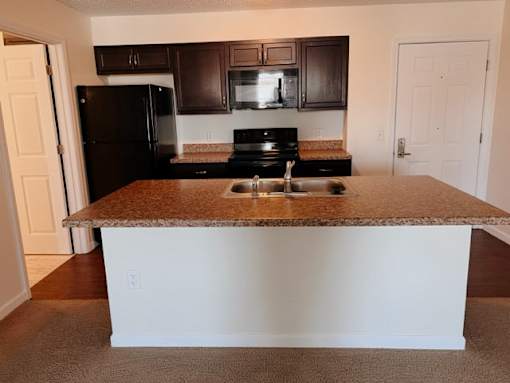 A kitchen with brown cabinets and a black refrigerator.