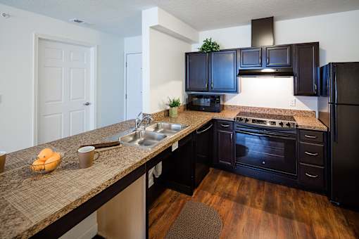 A kitchen with black cabinets and a granite countertop.