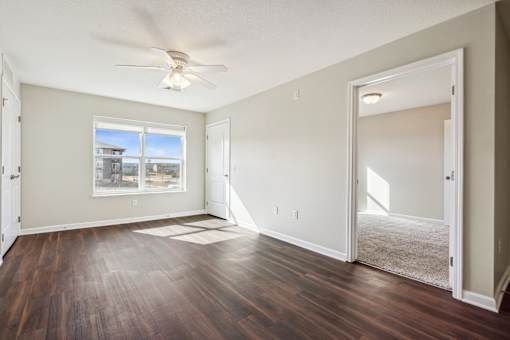 A room with a ceiling fan and a large window.