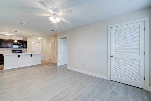 A spacious room with a ceiling fan and lighting fixtures.