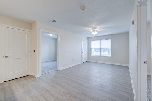 A spacious room with light wood flooring and white walls.