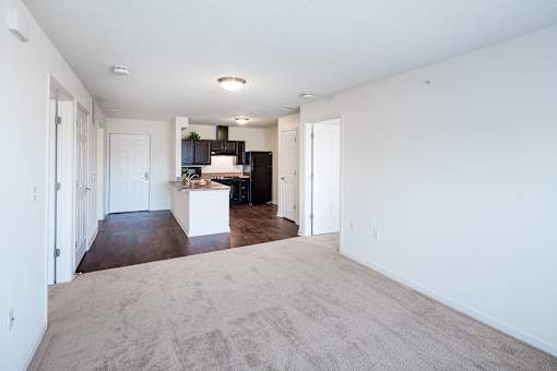 A spacious living room with a kitchen in the background.