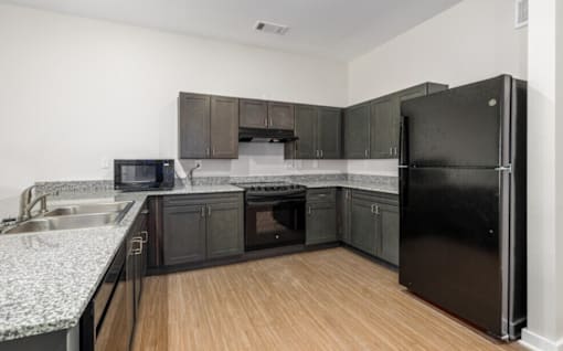 A kitchen with black cabinets and a black refrigerator.