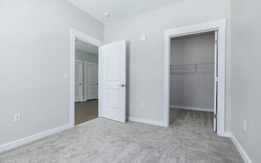 A room with a carpeted floor and two open doors.