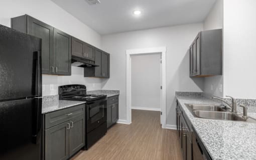 A kitchen with black cabinets and a white door.