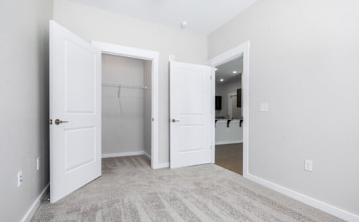 A room with two open doors and a carpeted floor.