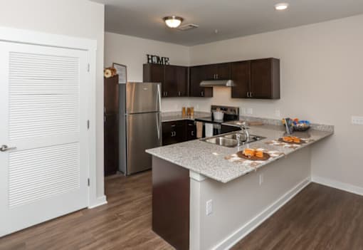 A kitchen with a refrigerator, sink, and cabinets.