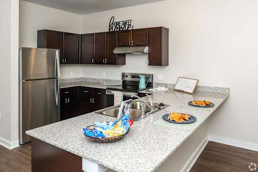 A kitchen with a granite countertop and a stainless steel refrigerator.