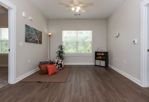 A room with a brown rug and a ceiling fan.
