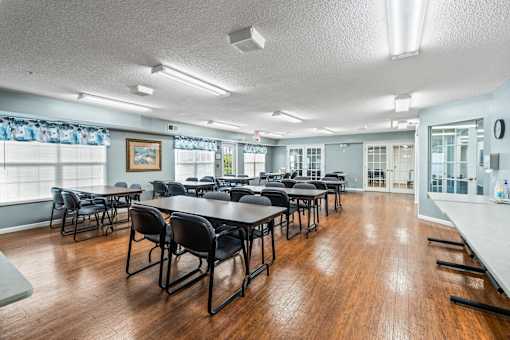 A room with tables and chairs and a painting on the wall.