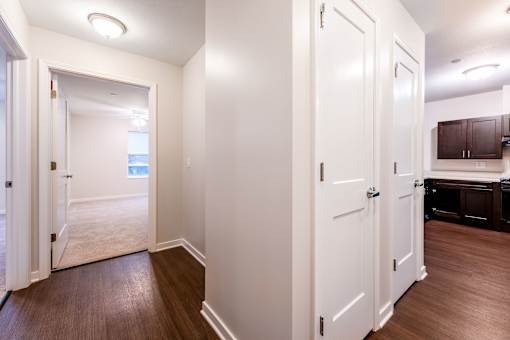A hallway with white doors and brown floors.