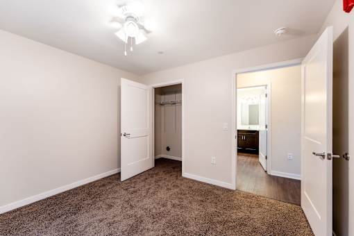 A room with a carpeted floor and a ceiling fan.