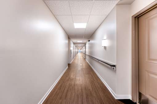 A long hallway with wood floors and white walls.