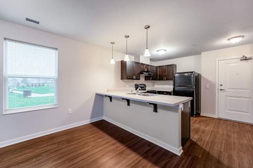 A kitchen with a white countertop and wooden floors.