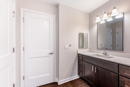 A white door is in a bathroom with a sink and mirror.