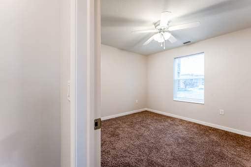 A room with a ceiling fan and carpeted floor.