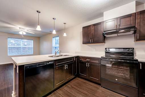 A kitchen with dark wood cabinets and black appliances.