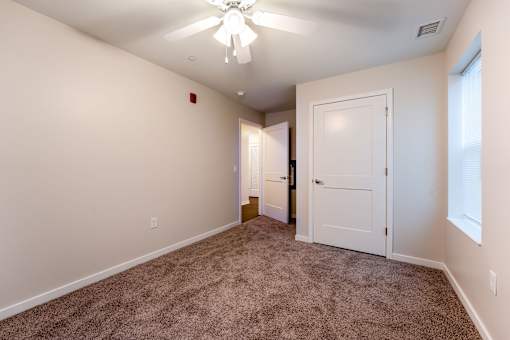 A room with a carpeted floor and a ceiling fan.
