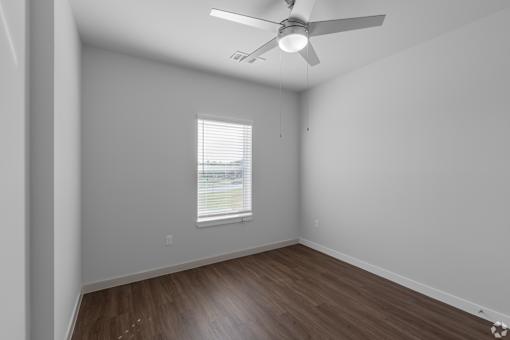 A room with a ceiling fan and a window with blinds.