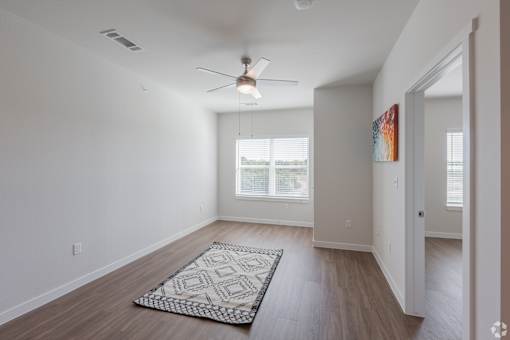 A room with a ceiling fan and a rug on the floor.